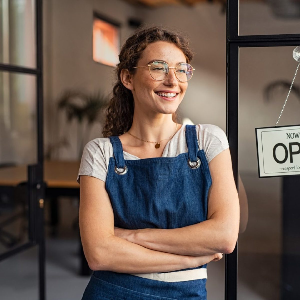 new business start-up owner standing in front of cafe with open sign